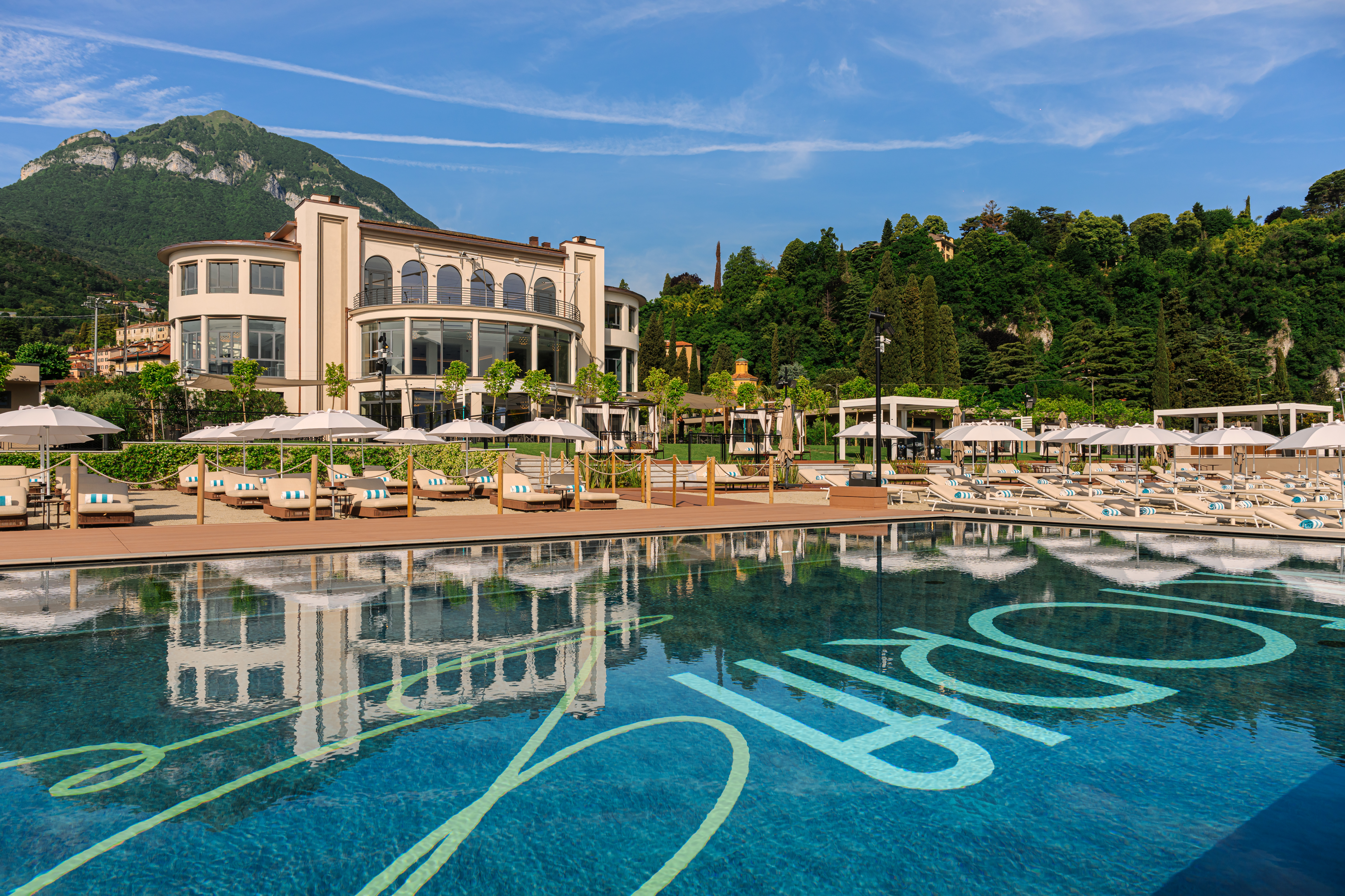 Grand Hotel Victoria Concept & Spa exterior view showing one of the hotel's pools with the ochre hotel building and lush hillsides behind