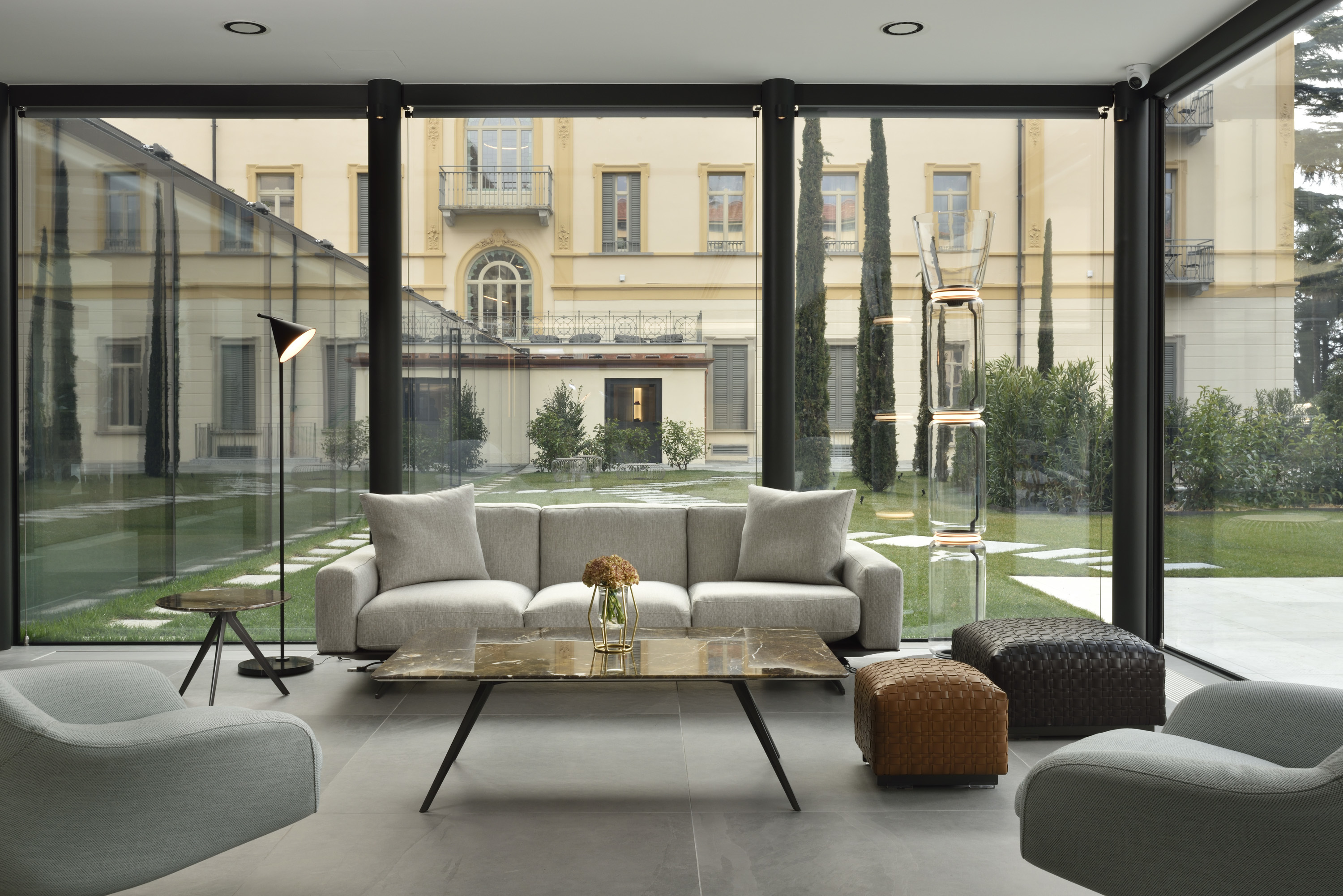 Grand Hotel Victoria Concept & Spa foyer with sleek monchromatic furnishings and floor-to-ceiling windows looking out on the green inner courtyard