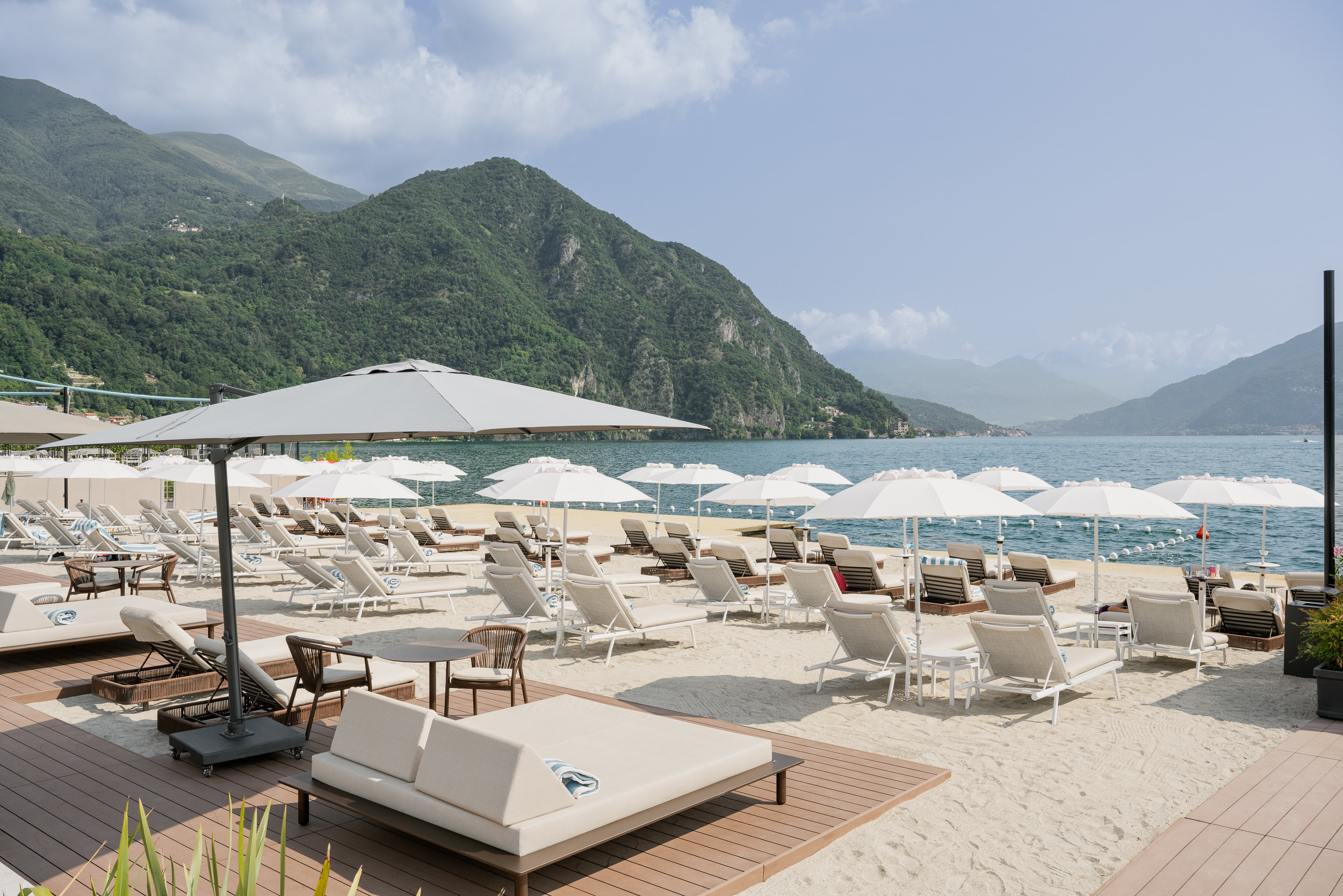 Grand Hotel Victoria Concept & Spa beach club, with white sun loungers and white parasols on white sand looking out across the lake