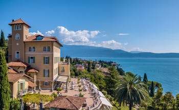 Exterior panorama with hotel building and terrace with view of the lake 