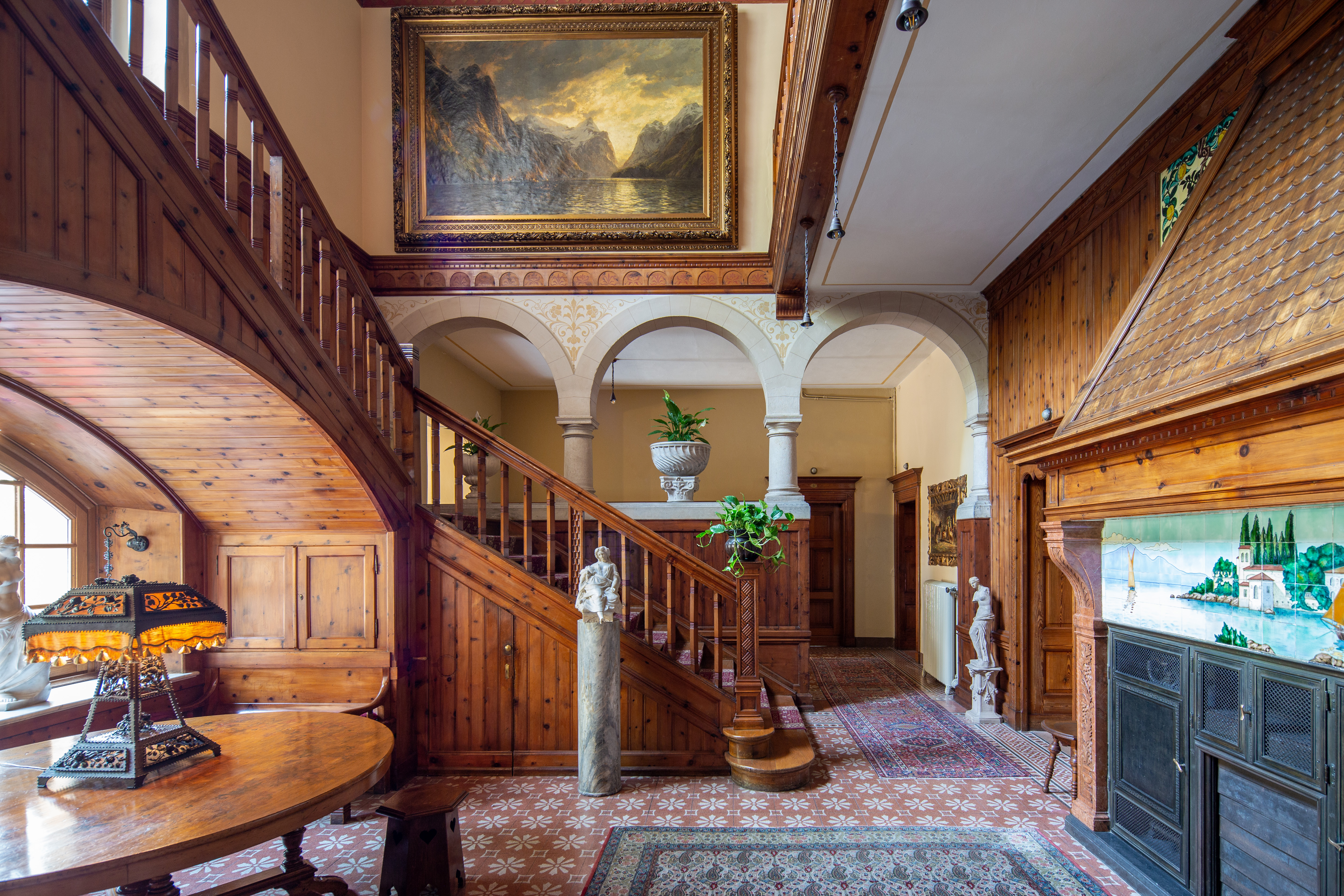Hallway and wooden staircase with artwork on walls