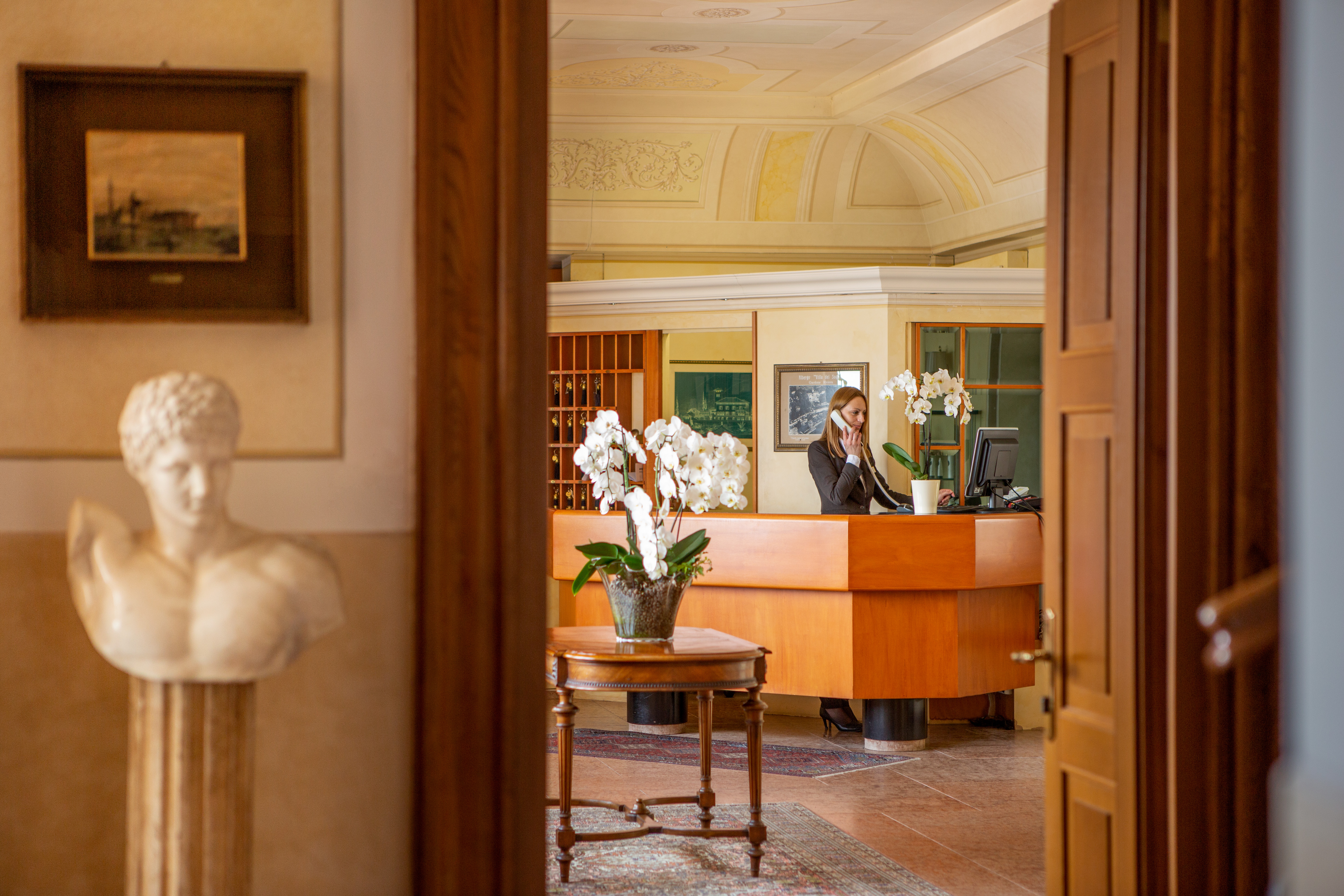 Reception desk with man behind and flowers on table in centre of room 