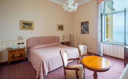 Standard room with chandelier, double bed, windows and artwork on the walls