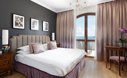 Superior room with double bed, chandelier and doors opening onto balcony 