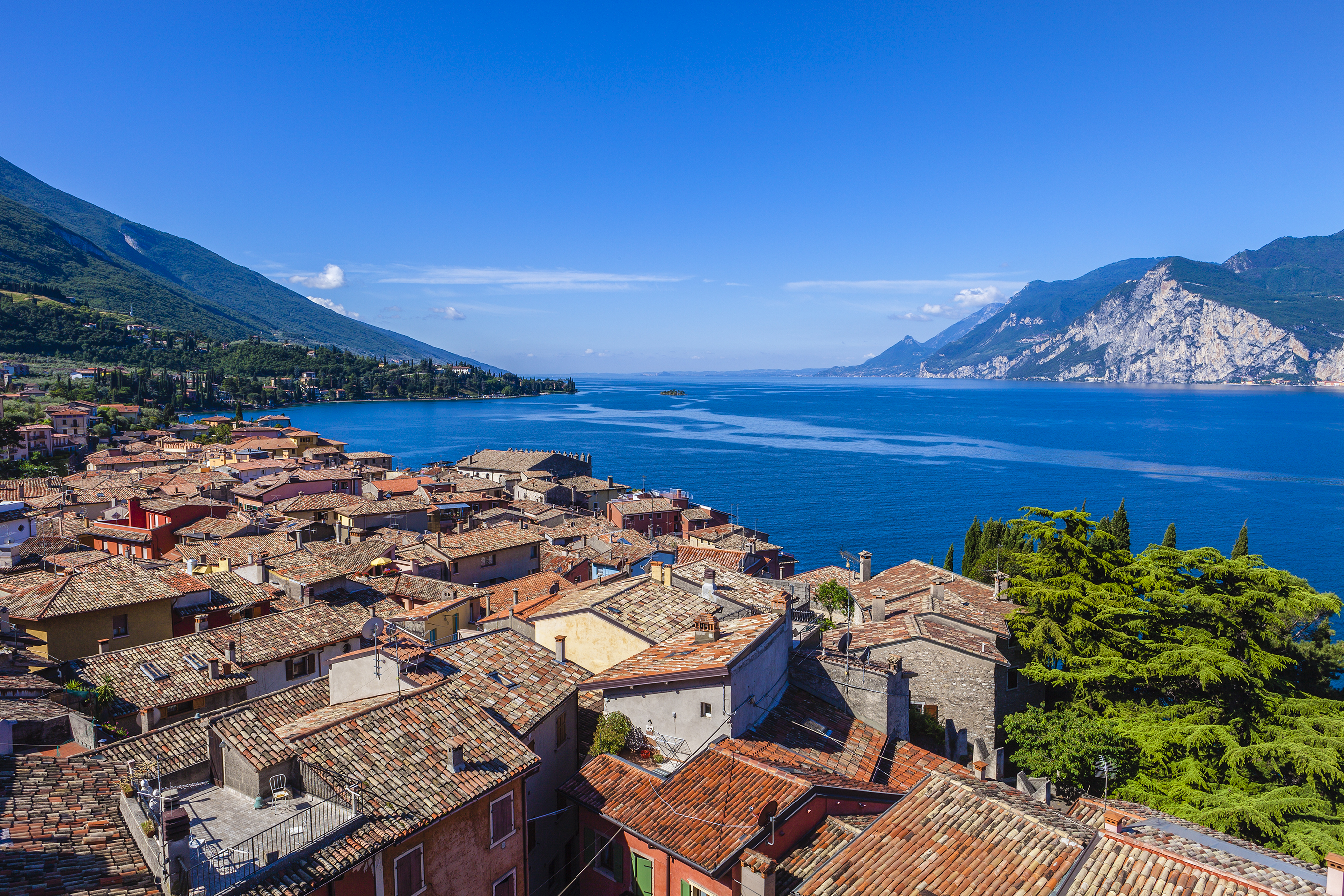 Aerial view of the terracotta roofs of the houses of Malcesine village on shore of deep blue Lake Garda
