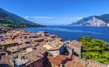 Aerial view of the terracotta roofs of the houses of Malcesine village on shore of deep blue Lake Garda