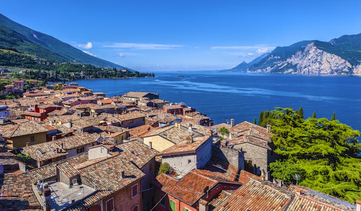Aerial view of the terracotta roofs of the houses of Malcesine village on shore of deep blue Lake Garda