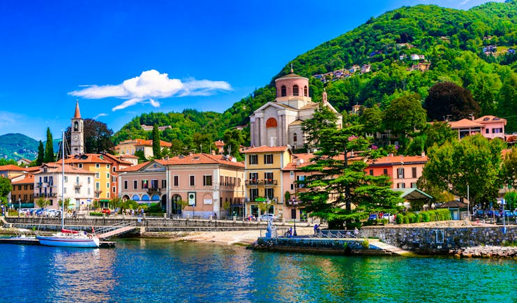 Village with church and houses with red roofs lining the waterfront of Lake Maggiore