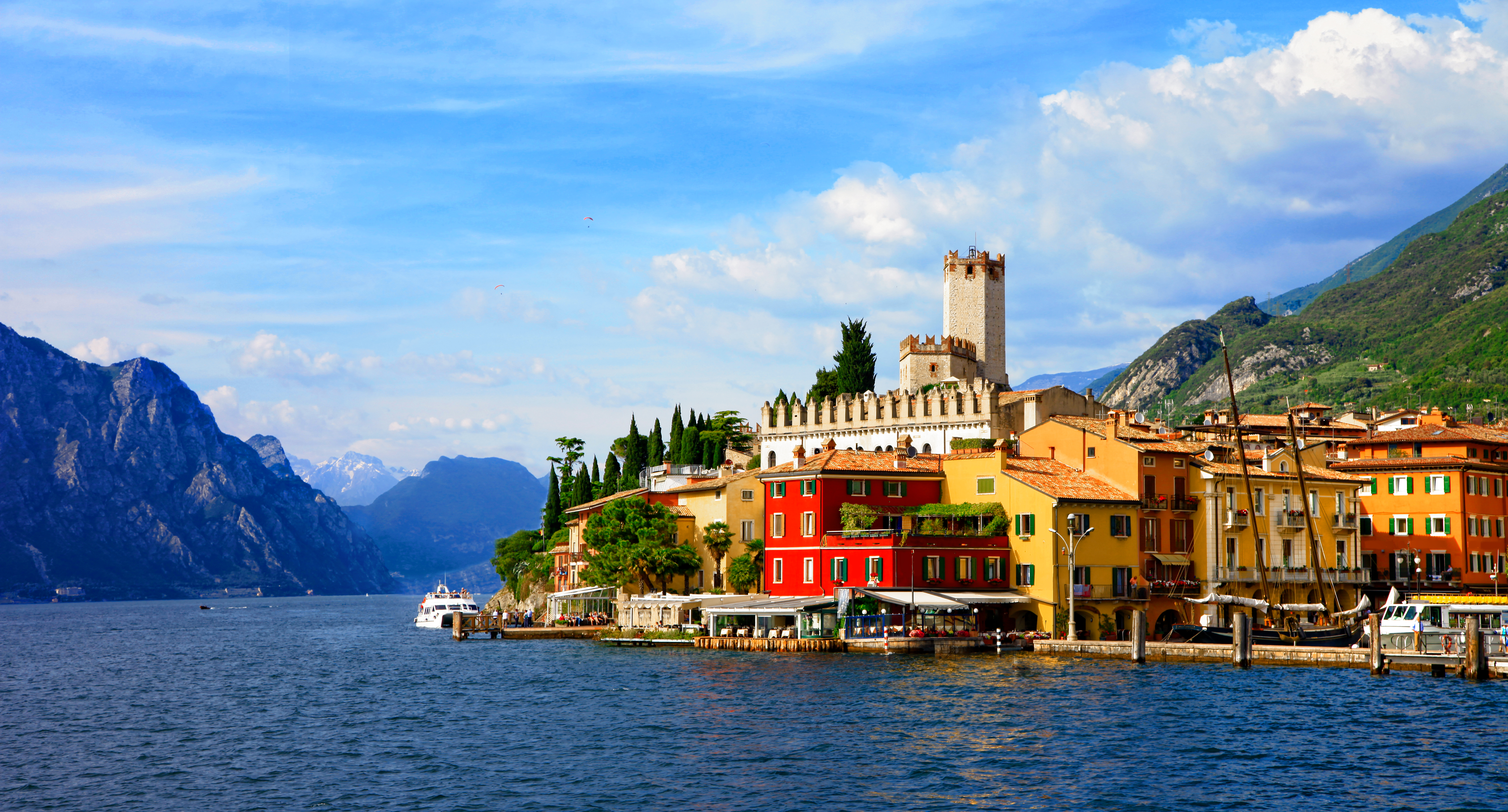 Sunlight village with castle tower on edge of deep blue Lake Garda