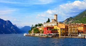 Sunlight village with castle tower on edge of deep blue Lake Garda