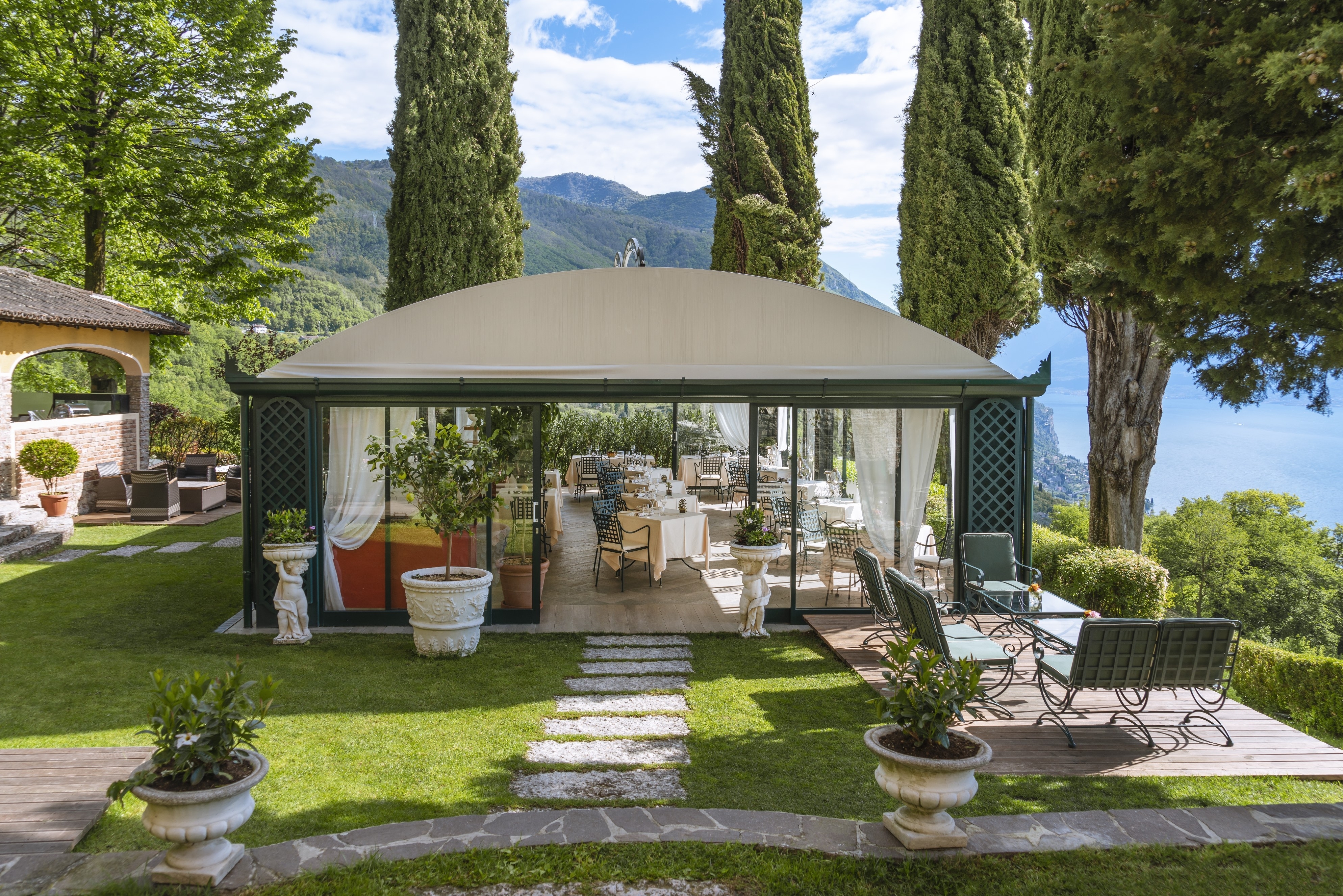 Villa Sostaga breakfast restaurant under dark green canopy with green lawns surrounding and lake views