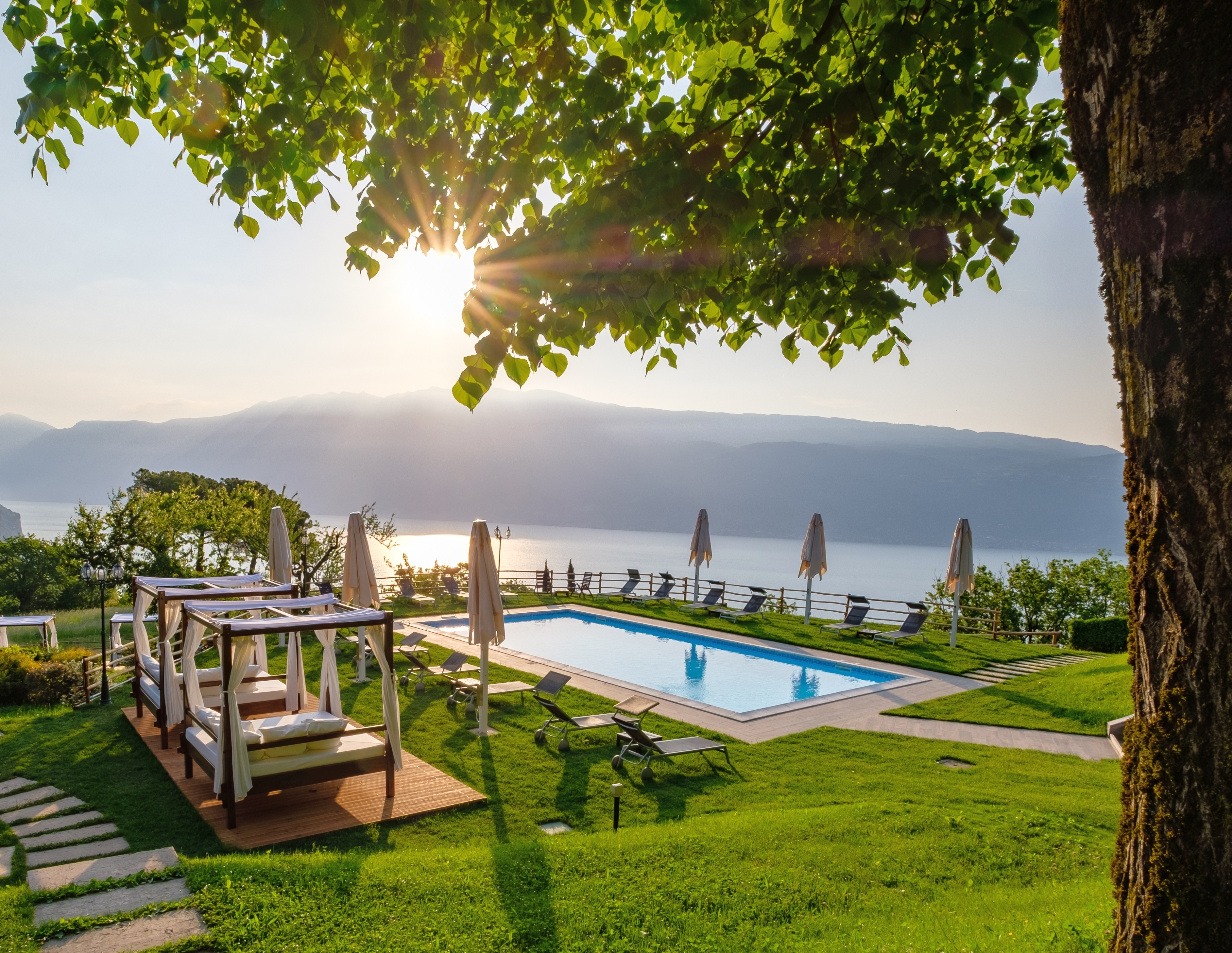 Villa Sostaga lakeview garden with pool and daybeds, at sunset