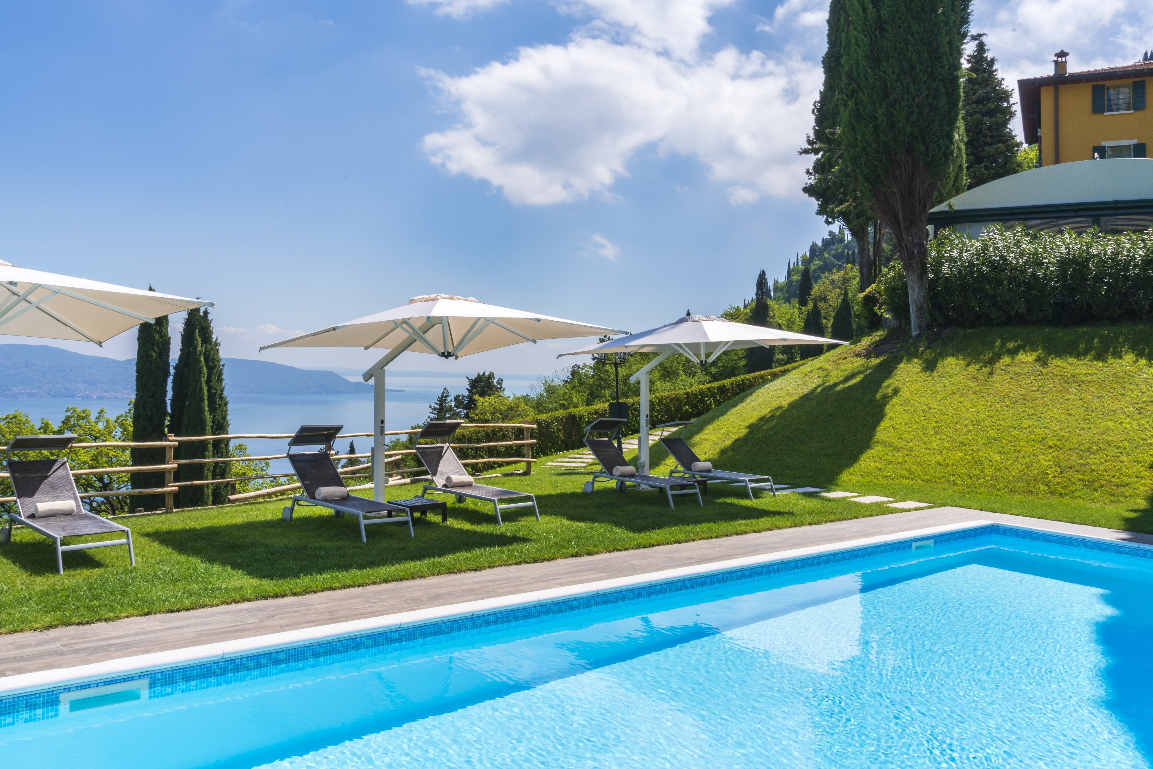 Villa Sostaga swimming pool with bright turquoise water, grassy poolside, and lake views