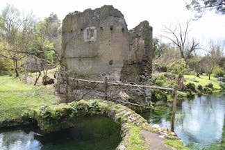 Ruined medieval building with footbridge over river in foreground