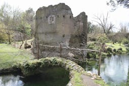 Ruined medieval building with footbridge over river in foreground