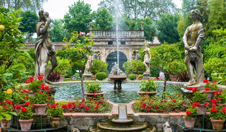 Statues, red flowers, fountains and water features at Palazzo Pfanner Tuscany