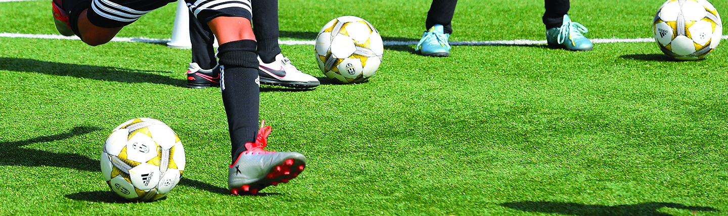 Footballs being kicked on grass