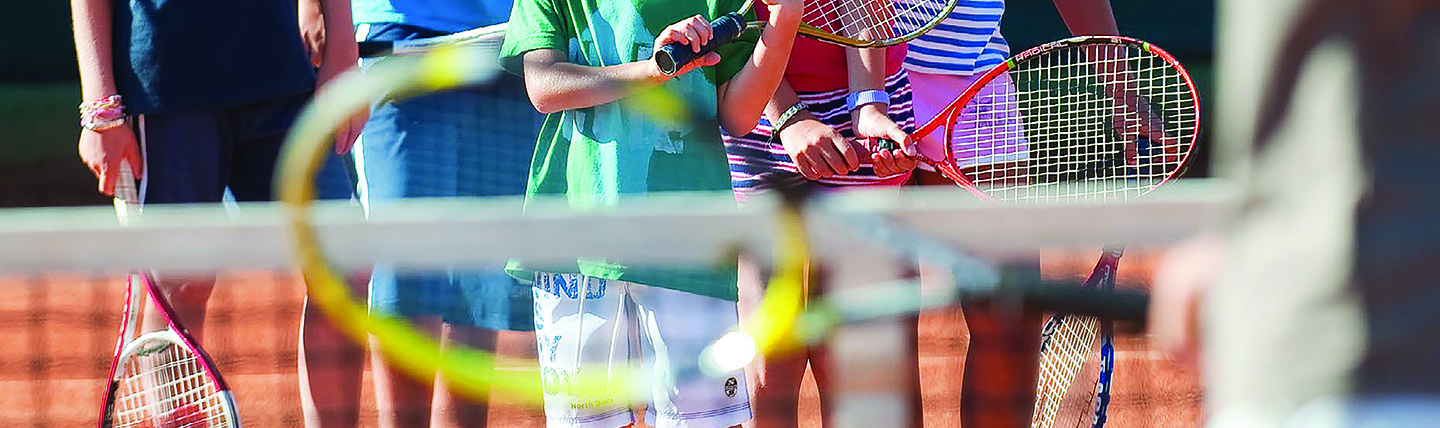Tennis rackets being held by children at net