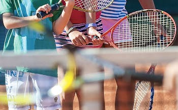 Tennis rackets being held by children at net