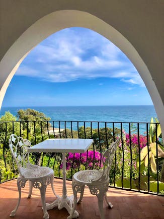 Balcony with chairs and table overlooking sea