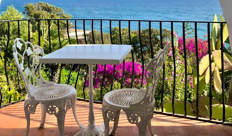 Balcony with chairs and table overlooking sea