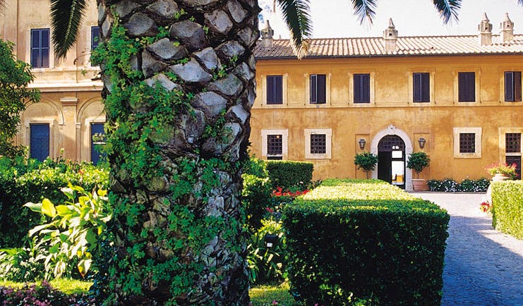 La Posta Vecchia Latium pathway leading to hotel tree shrubs building