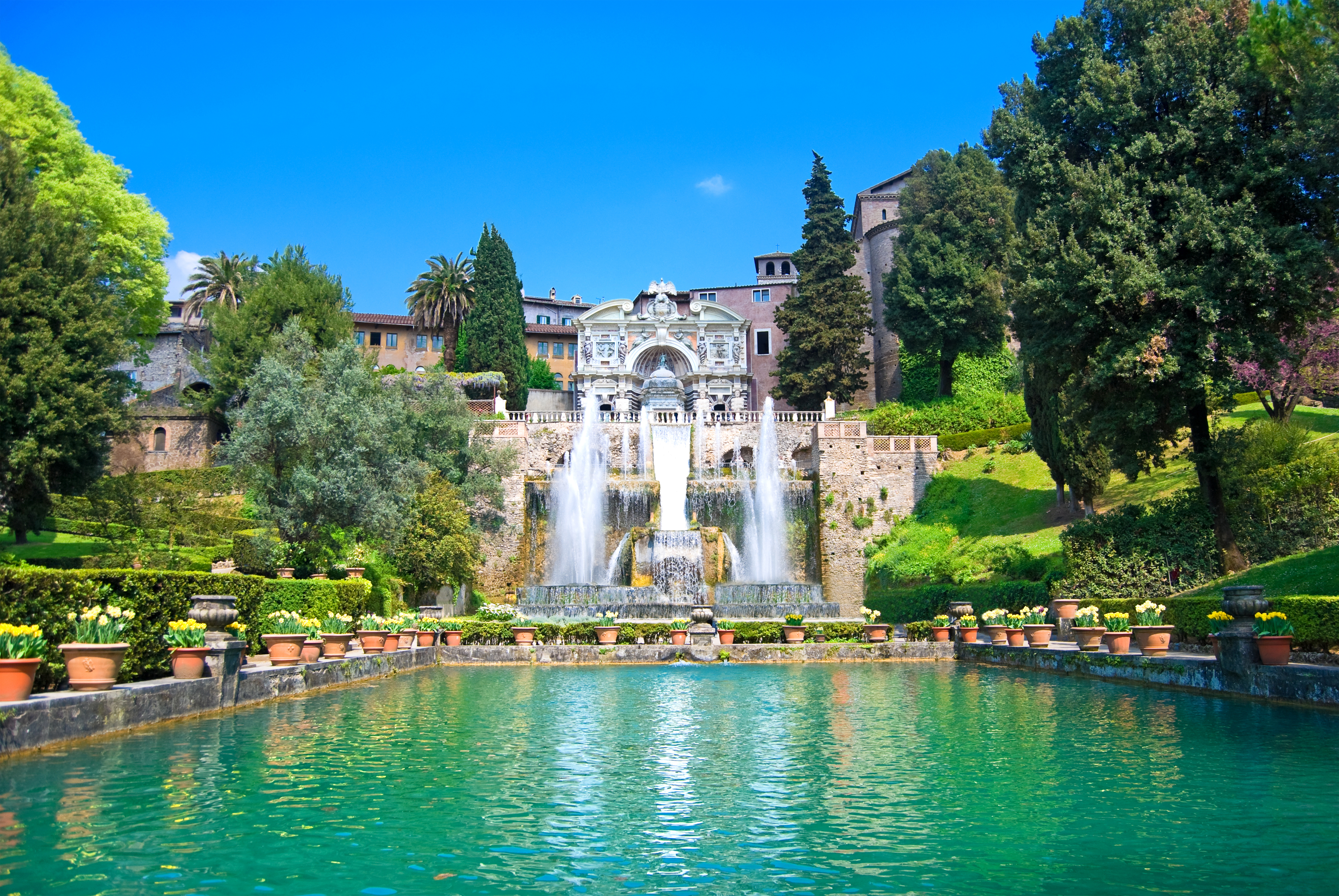 Turquoise pond with jets of water from fountains with terraced stone landscape and trees at Villa d'Este Tivoli near Rome