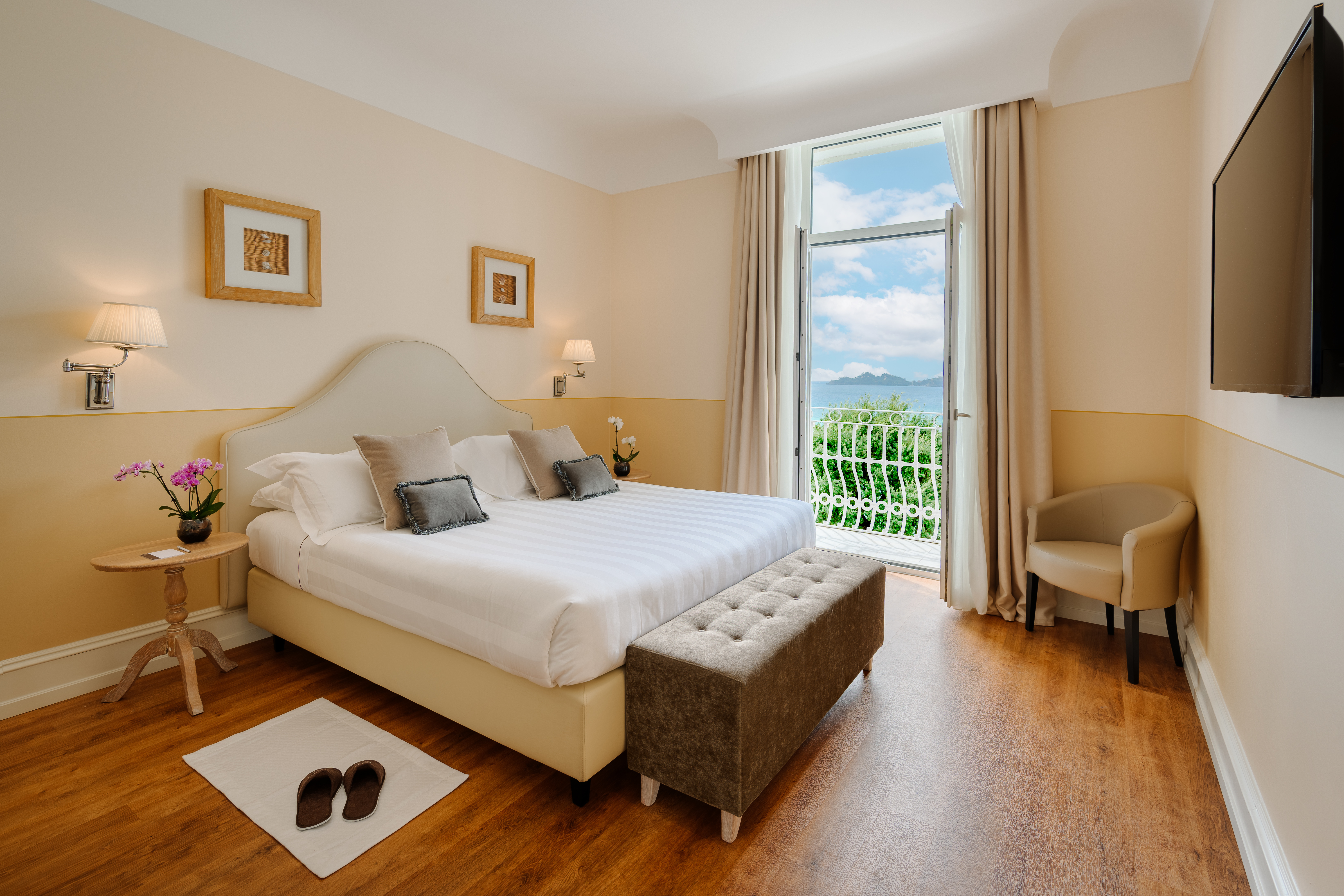 Grand Hotel Bristol Resort & Spa Deluxe Sea Front Room, with warm neutral colours, and double doors opening onto a juliet balcony with sea views