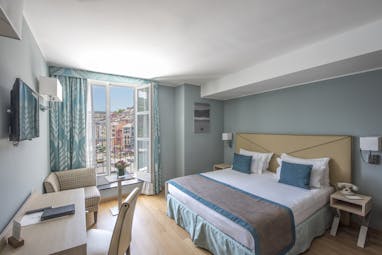 Executive room with blue colour scheme, large double bed, double doors opening out onto balcony and television 