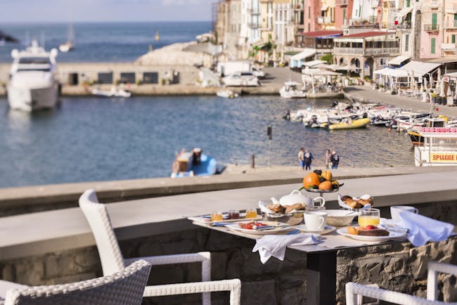 Breakfast laid out on tables outdoors on terrace with views of port 