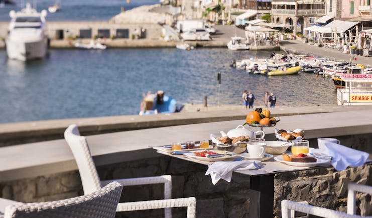 Breakfast laid out on tables outdoors on terrace with views of port 