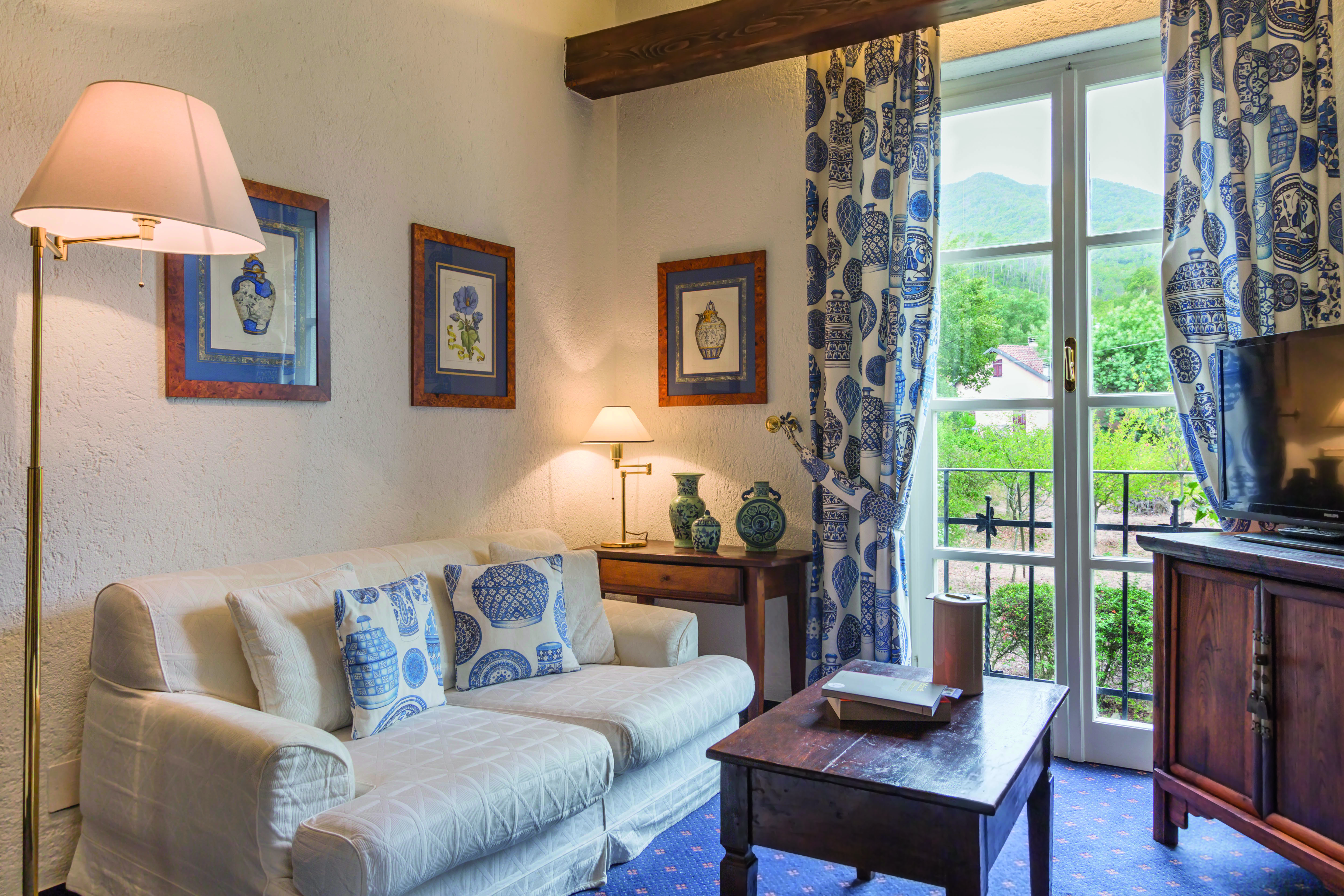 Sofa and lamps, blue and white scheme, with French window behind at La Meridiana