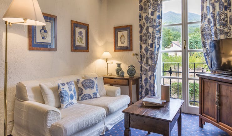 Sofa and lamps, blue and white scheme, with French window behind at La Meridiana