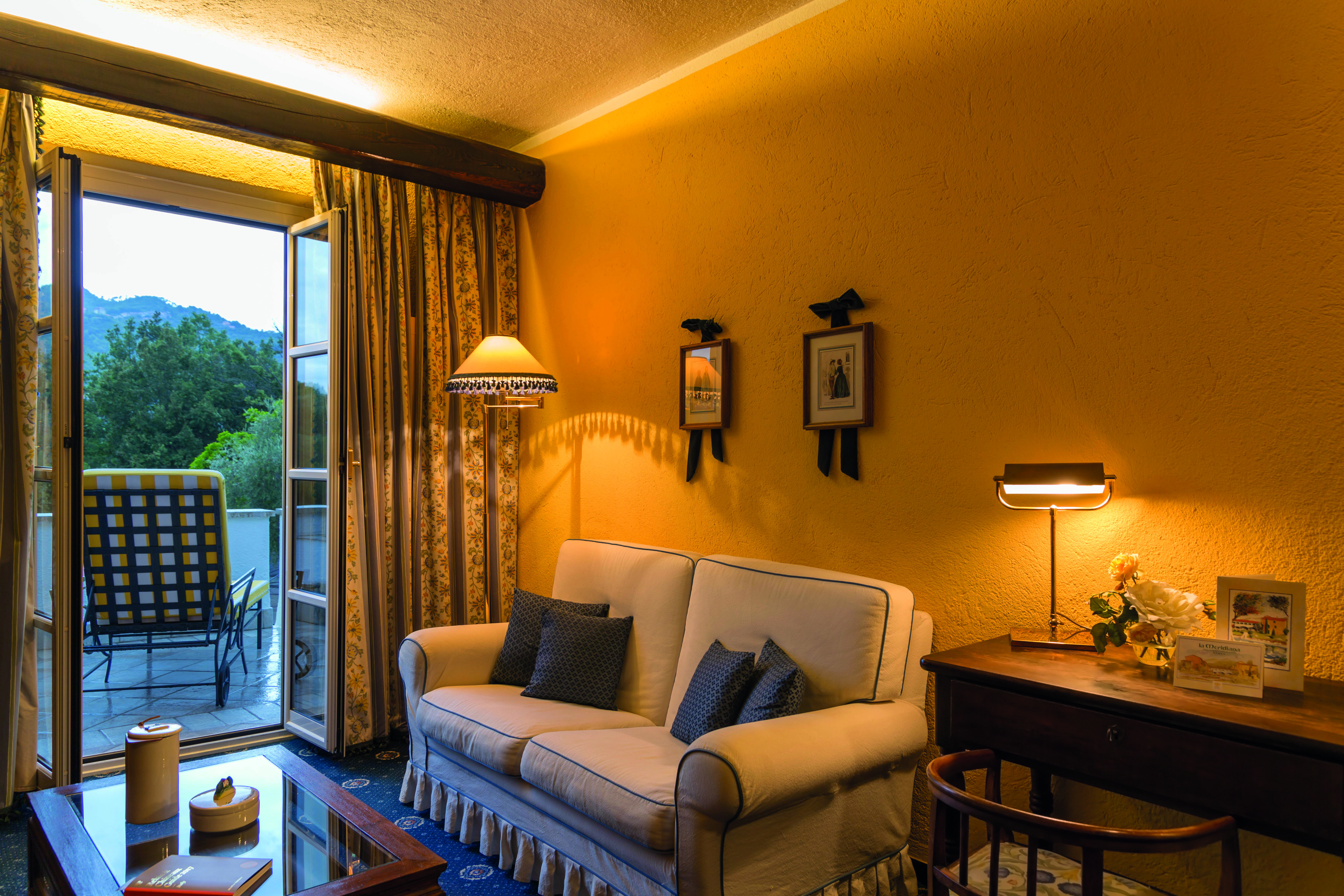 Sofa and balcony with open door, yellow walls and lamps on at La Meridiana