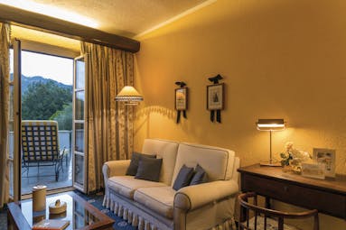 Sofa and balcony with open door, yellow walls and lamps on at La Meridiana