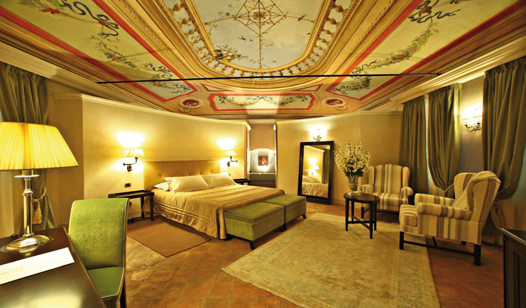 Relais Sant'Uffizio Piemonte suite Sant Uffizio bed chairs modern décor ornately painted ceiling