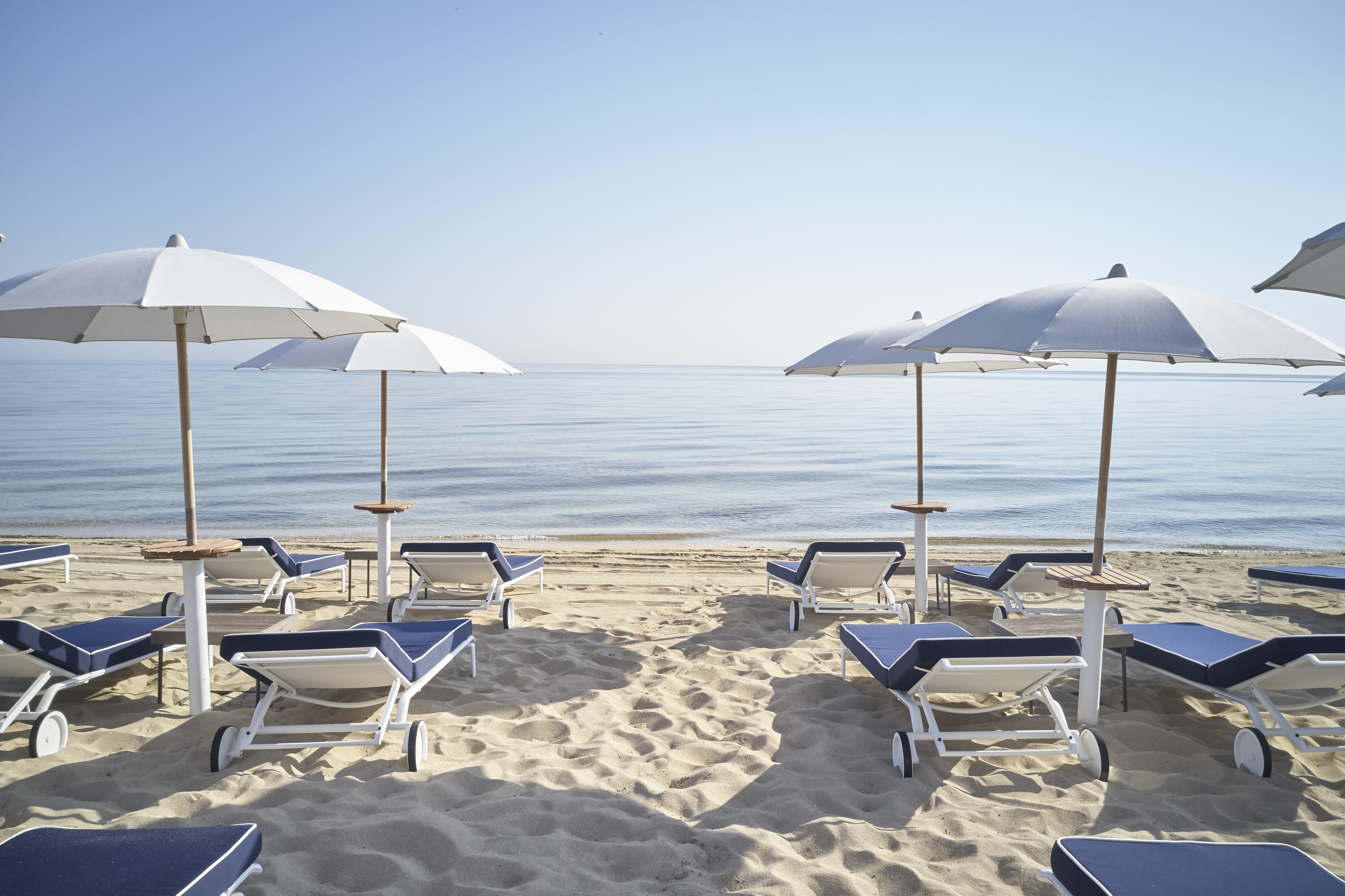 Sandy beach with whie umbrellas at Torre Maizza