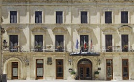 Facade in beige stone with long windows on three floors of the Patria Palace Lecce