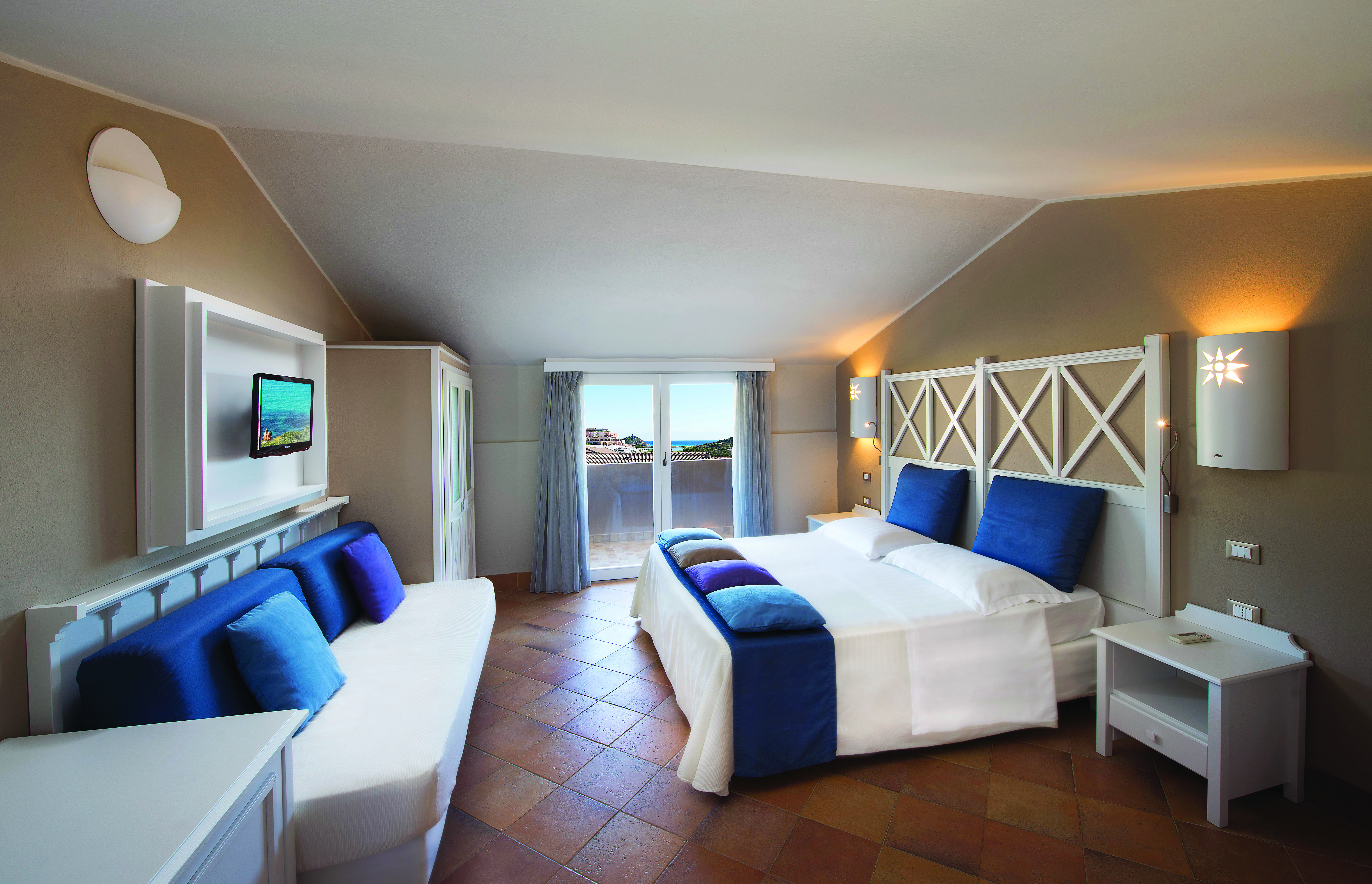 Second room in the family garden cottage with another double bed, balcony, telvision and white blue and purple colour scheme