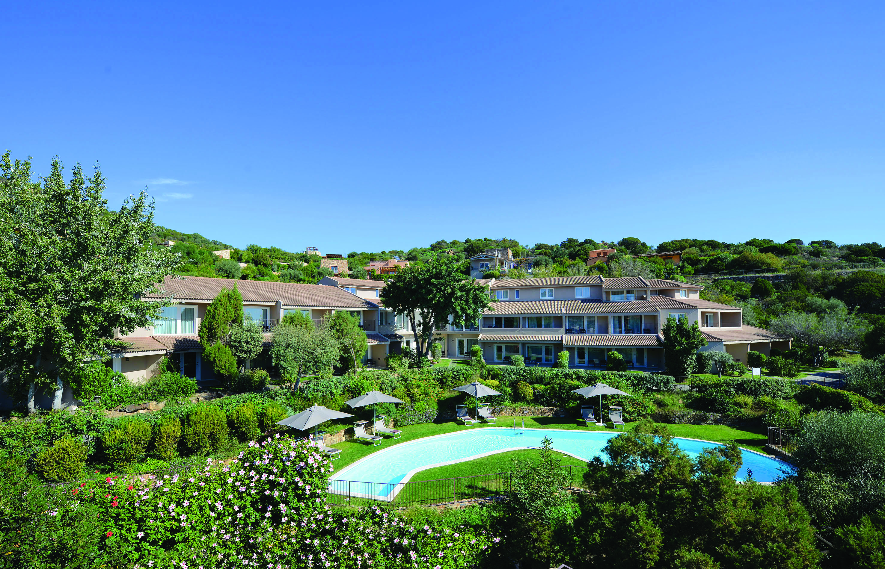 Hotel overview of the Chia Laguna with greenery surrounding the pool
