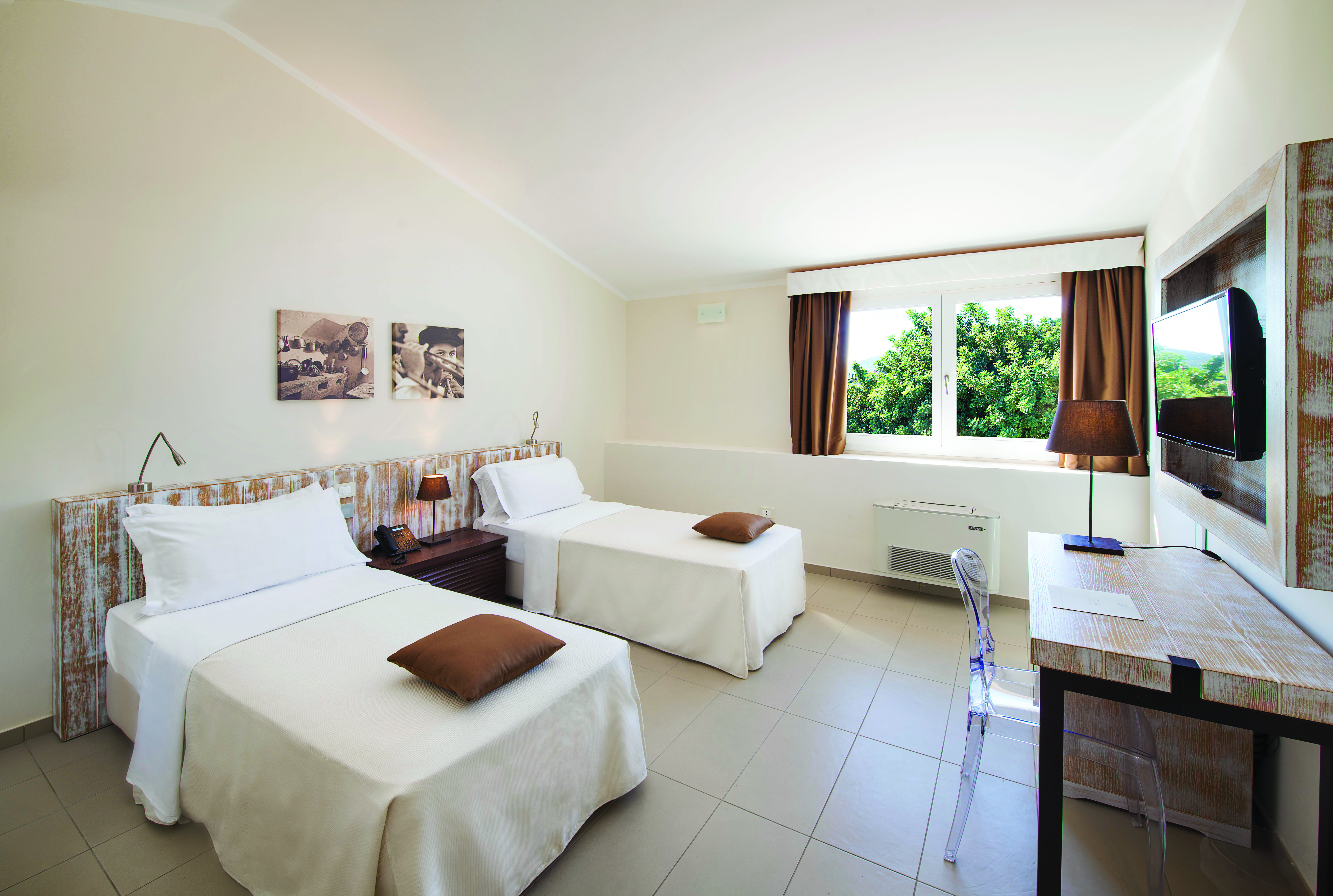 White and brown coloured room with with two twin beds and a desk 