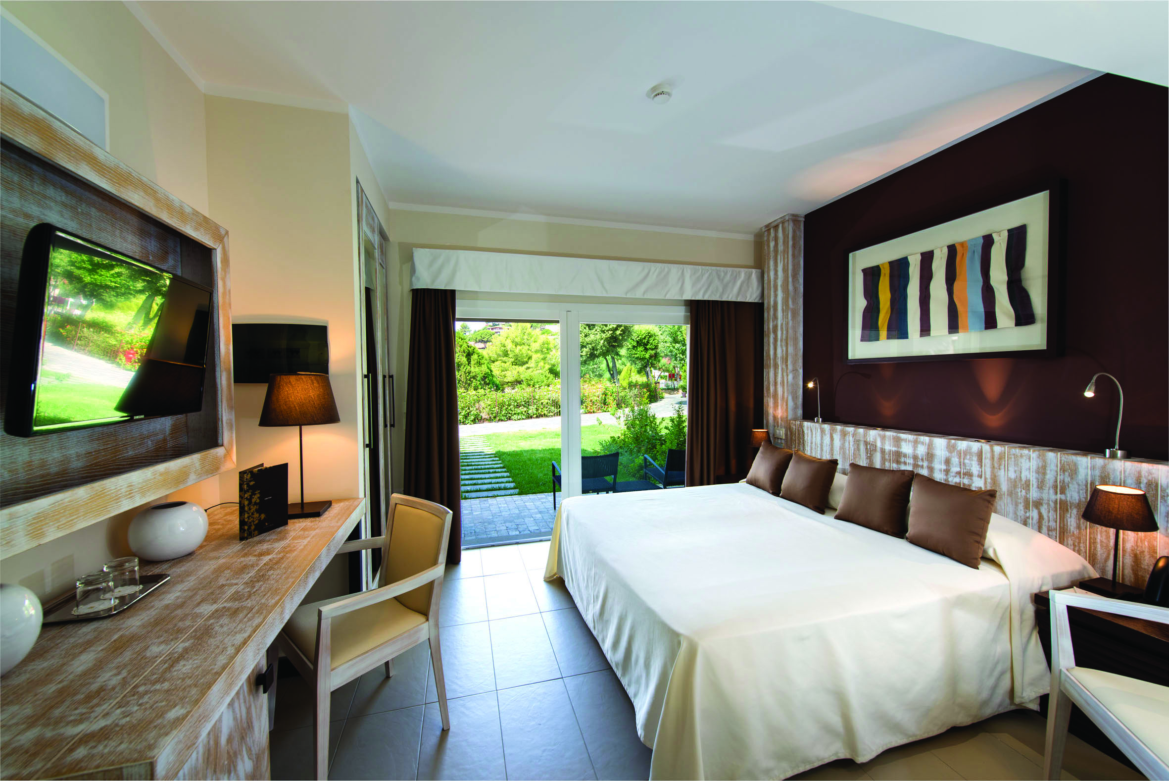 Oasi Garden room bedroom with largre bed, television and double doors opening up onto a terrace garden