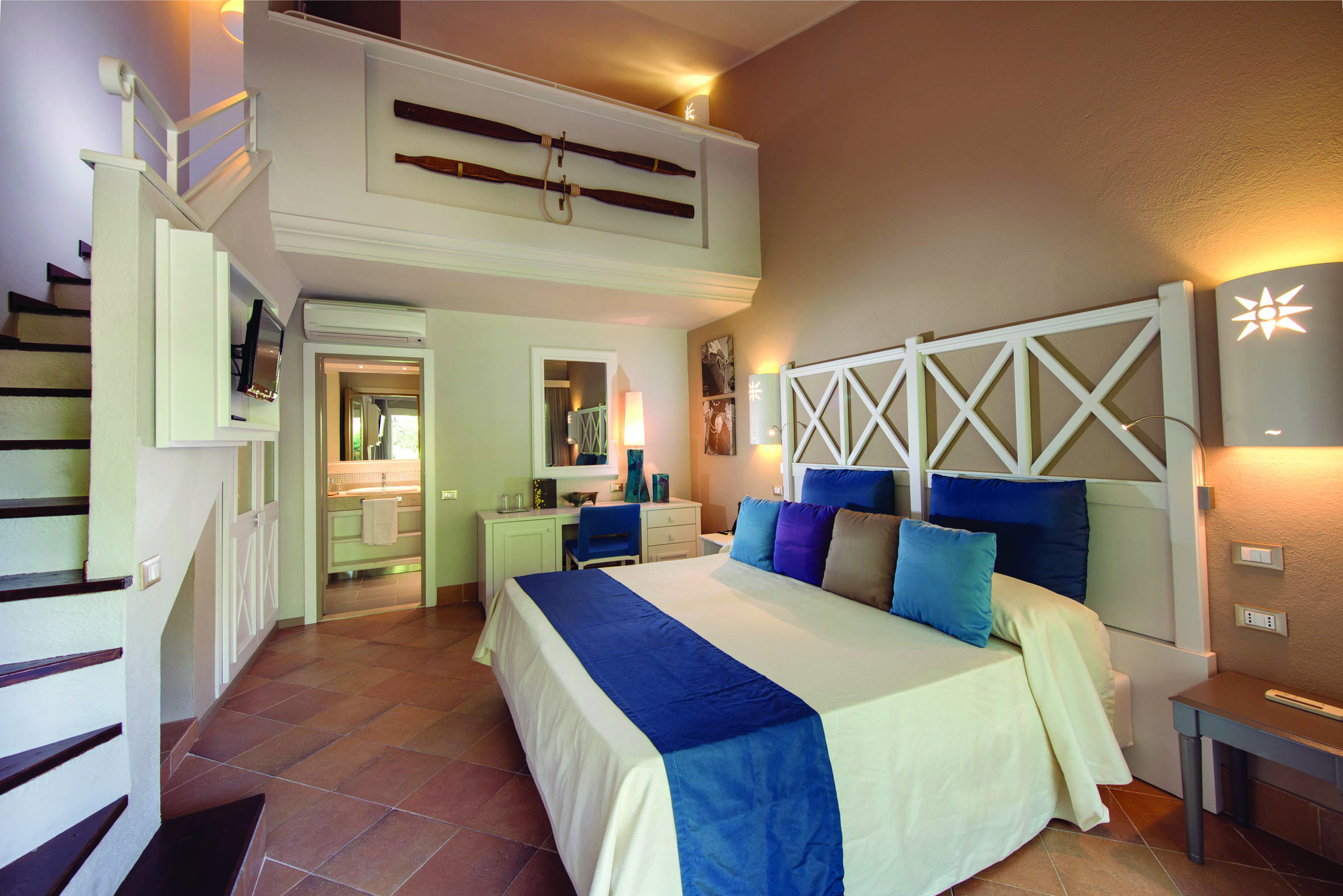 Chia Laguna Superior Family Cottage with a large bed, ensuite, two floors with a staircase leading upstairs 