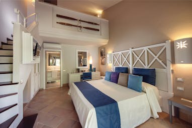 Chia Laguna Superior Family Cottage with a large bed, ensuite, two floors with a staircase leading upstairs 