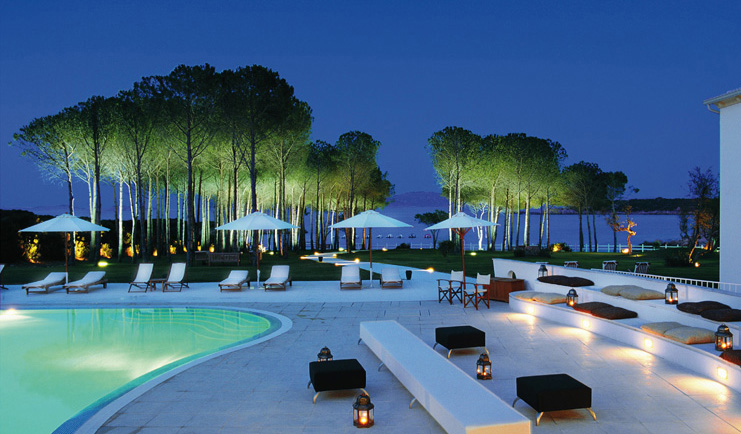Hotel La Coluccia Sardinia poolside at night sun loungers umbrellas sea in background