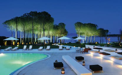 Hotel La Coluccia Sardinia poolside at night sun loungers umbrellas sea in background