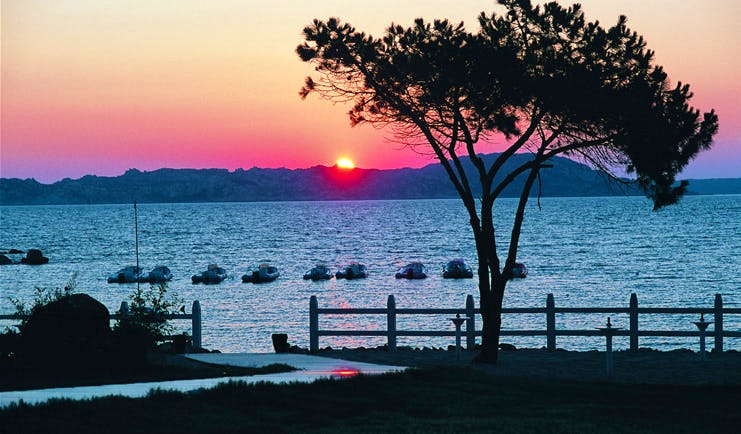 Hotel La Coluccia Sardinia sunset over the sea boats on the water