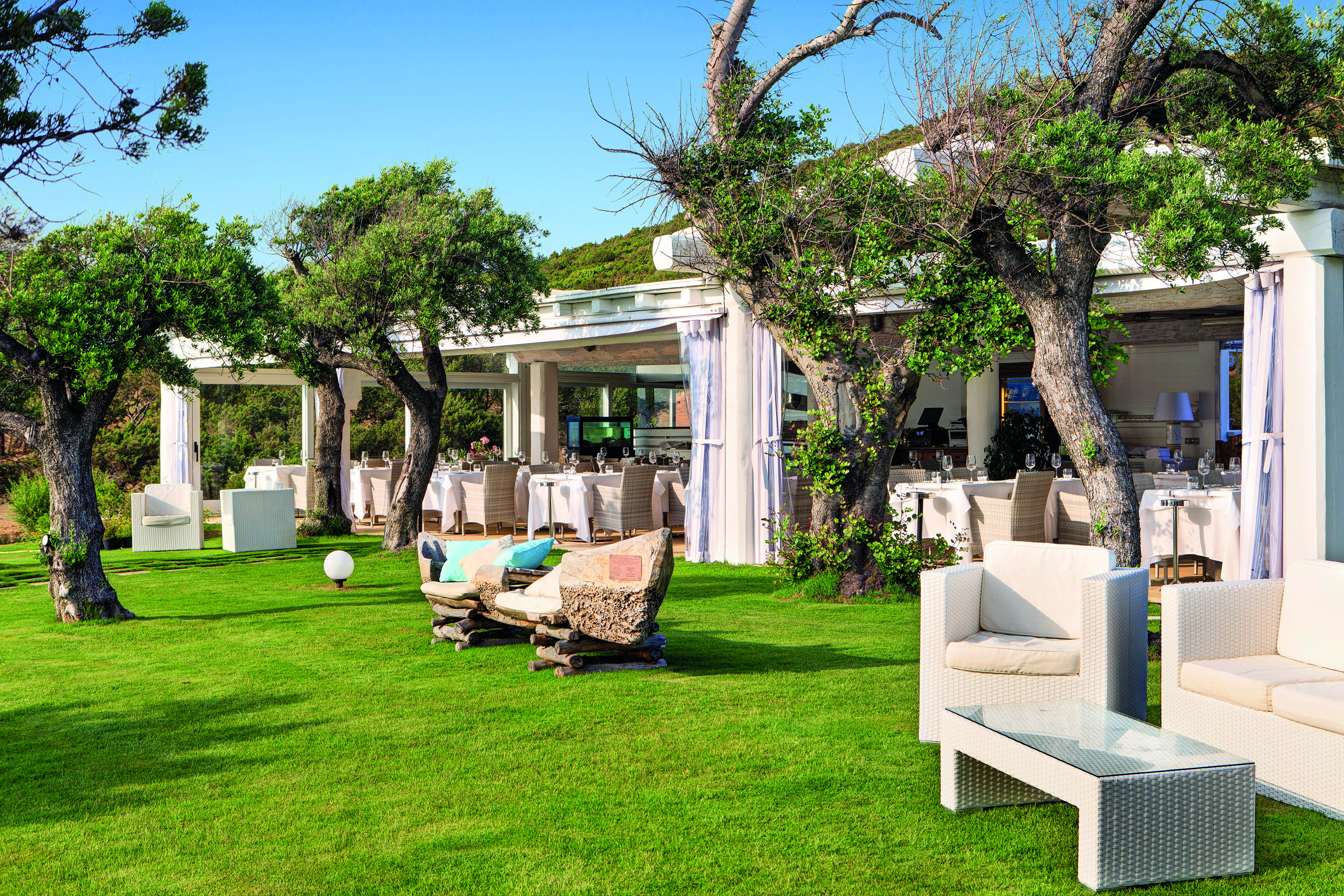 La Rocca Sardinia gardens outdoor seating area lawns trees restaurant in the background