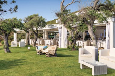 La Rocca Sardinia gardens outdoor seating area lawns trees restaurant in the background