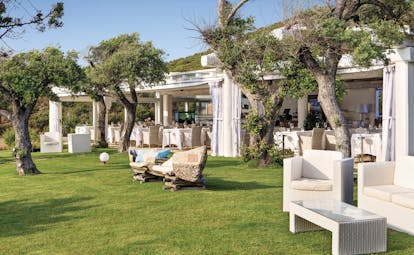 La Rocca Sardinia gardens outdoor seating area lawns trees restaurant in the background